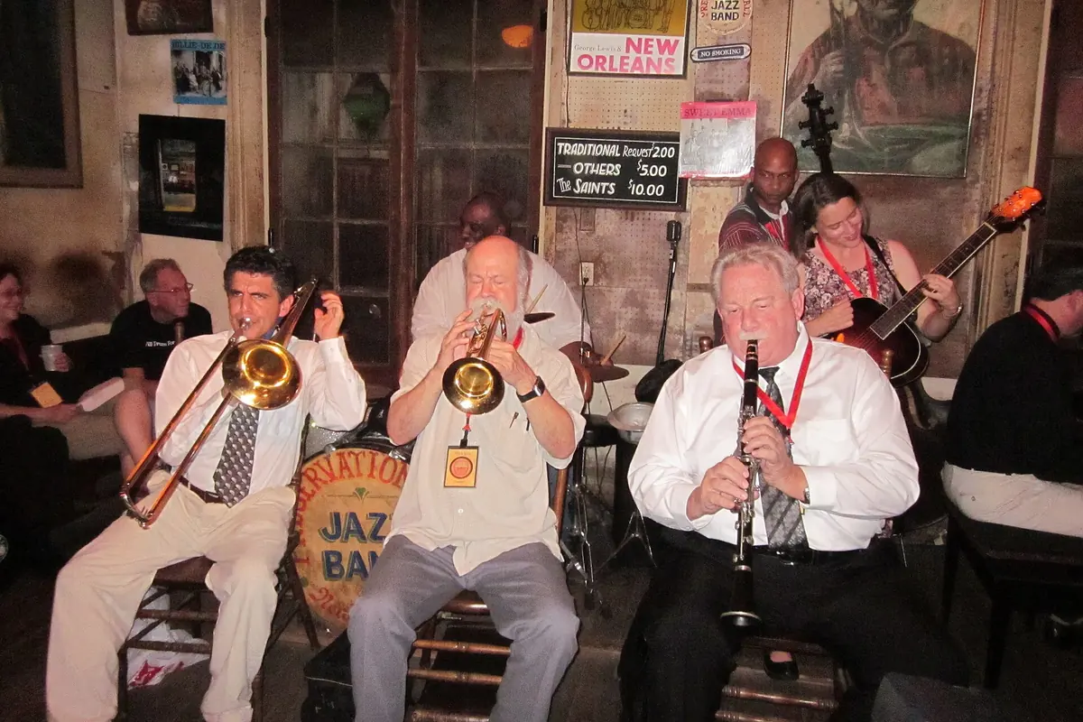 Тромбон, труба и кларнет звучат бок о бок в руках трёх музыкантов в Preservation Hall в Новом Орлеане